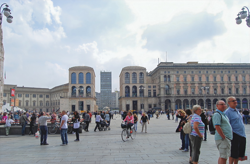 10 - A view across the bustling Piazza del Duomo in Milan, Italy, featuring the iconic symmetrical Palazzo dell'Arengario buildings in the background